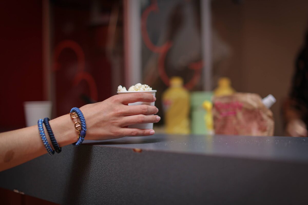 Une main attrape un gobelet de pop-corn sur le comptoir de la fête