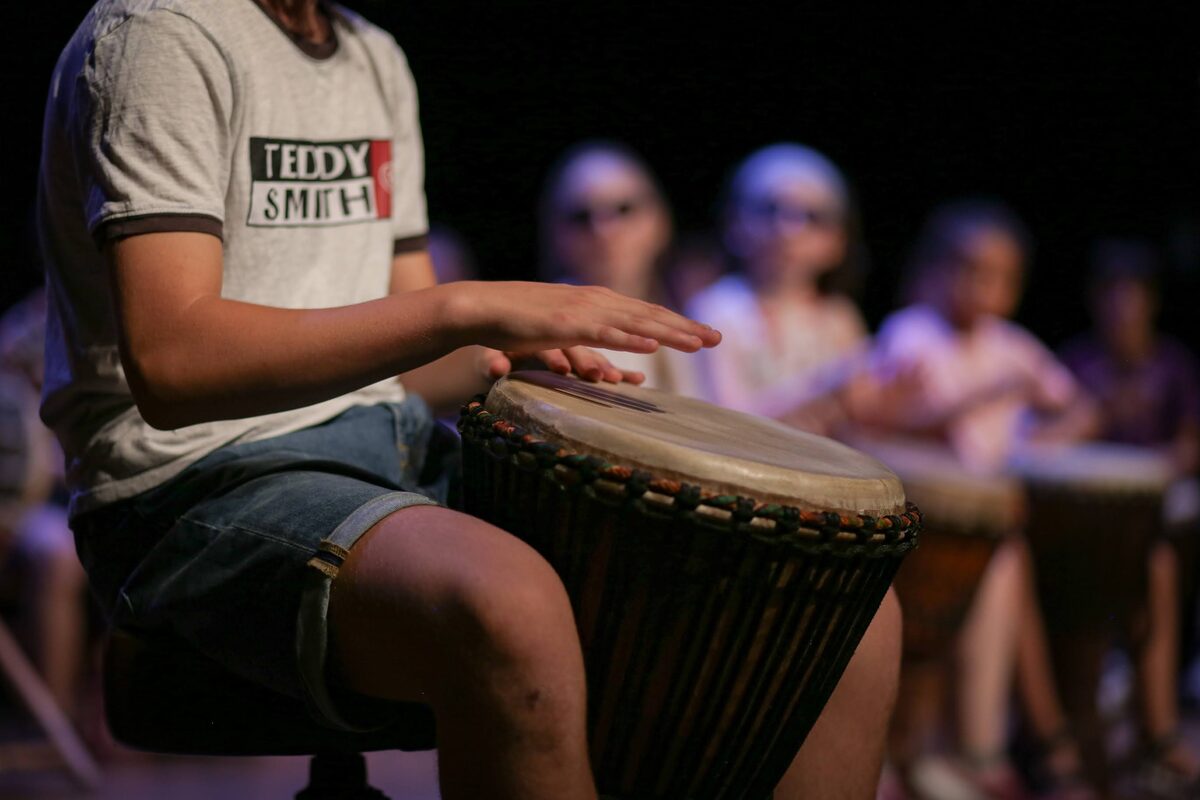 Un jeune percussionniste joue du djembé devant le groupe