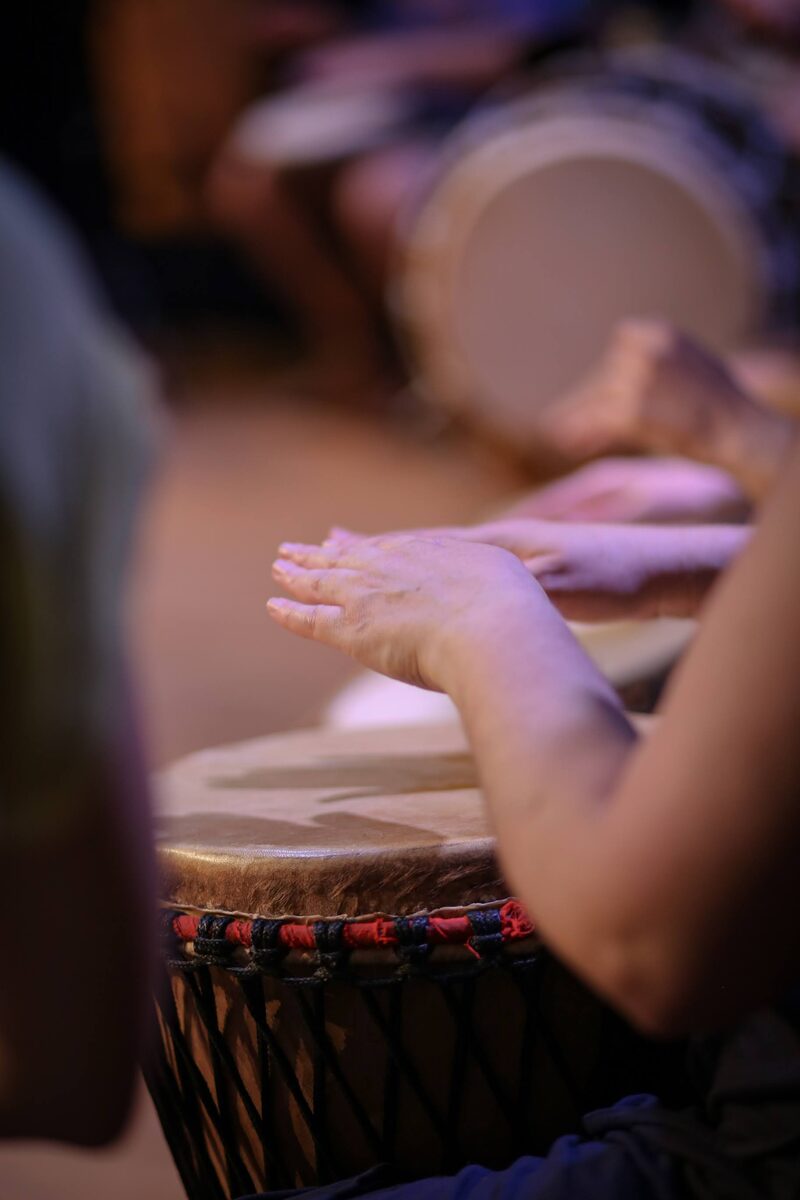 Mains d'enfants et d'adultes réunies sur les peaux des djembés